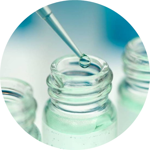 a pipette tip releasing a drop of liquid over a vial